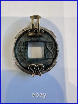 Chinese coin pendant, set in a gold-toned frame. 10K