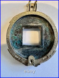 Chinese coin pendant, set in a gold-toned frame. 10K