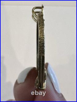 Chinese coin pendant, set in a gold-toned frame. 10K