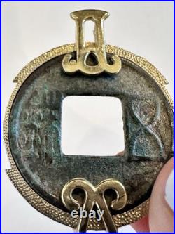 Chinese coin pendant, set in a gold-toned frame. 10K